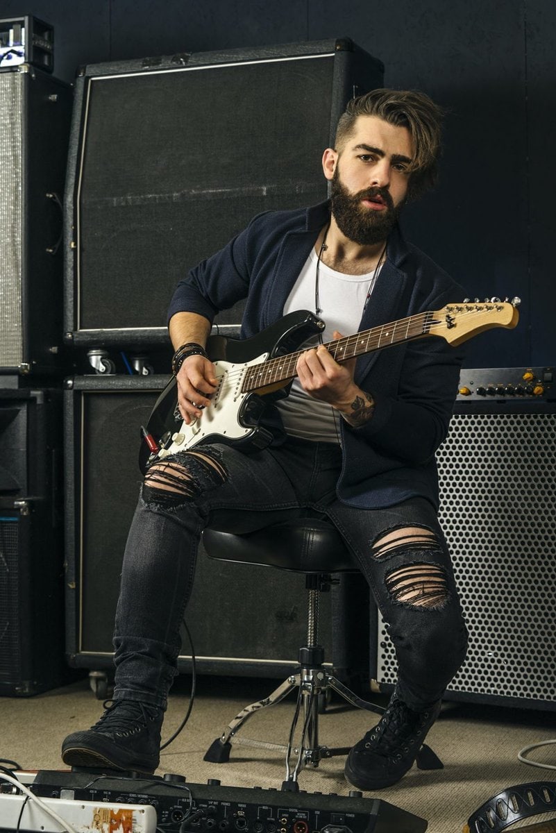 bearded man playing guitar in a music studio e1648783797853