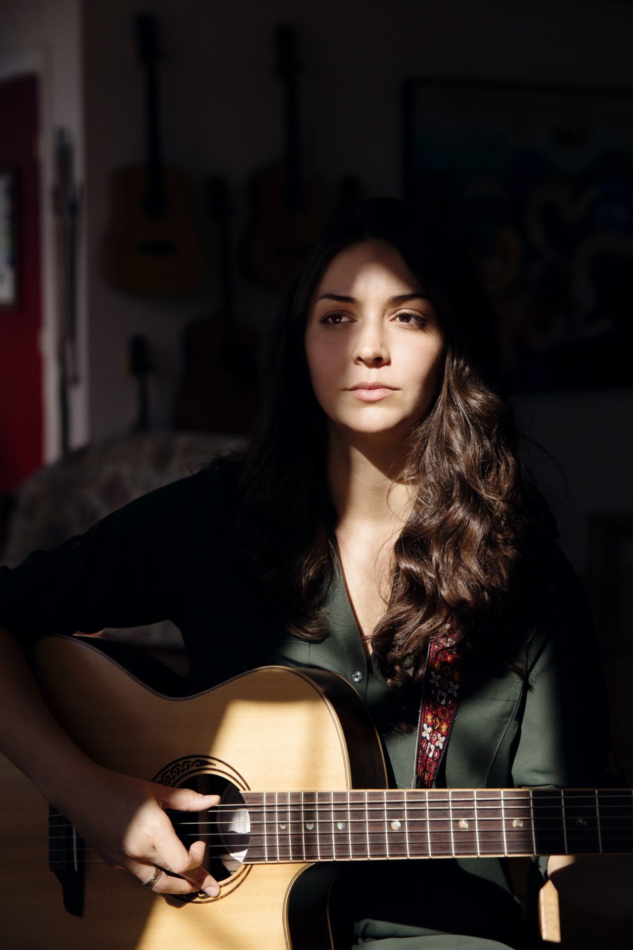 thoughtful woman playing guitar at home e1648783906639